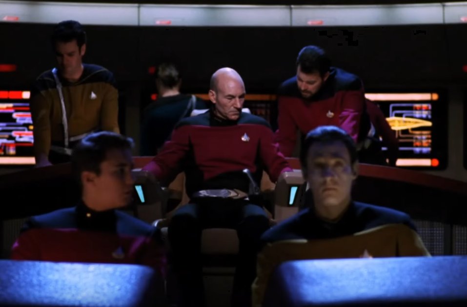 Frontal view of the full crew ready at their stations, Picard can be seen with a belt across his lap with Riker talking in his ear